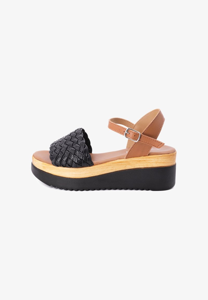 Sandali platform in pelle intrecciata nera con cinturino alla caviglia beige, caratterizzati da un sottopiede effetto legno e una suola in gomma nera con scanalature.