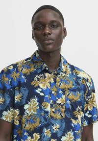 Cămașă cu mâneci scurte, cu nasturi, de culoare bleumarin, având un model floral vibrant în nuanțe de albastru și auriu pe un material ușor.