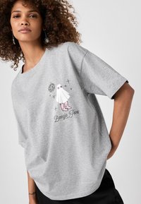 Grå oversized t-shirt lavet af bomuld. Har et grafikmotiv af en karakter med en discokugle og teksten "Boogie Fever" med rosa accenter.