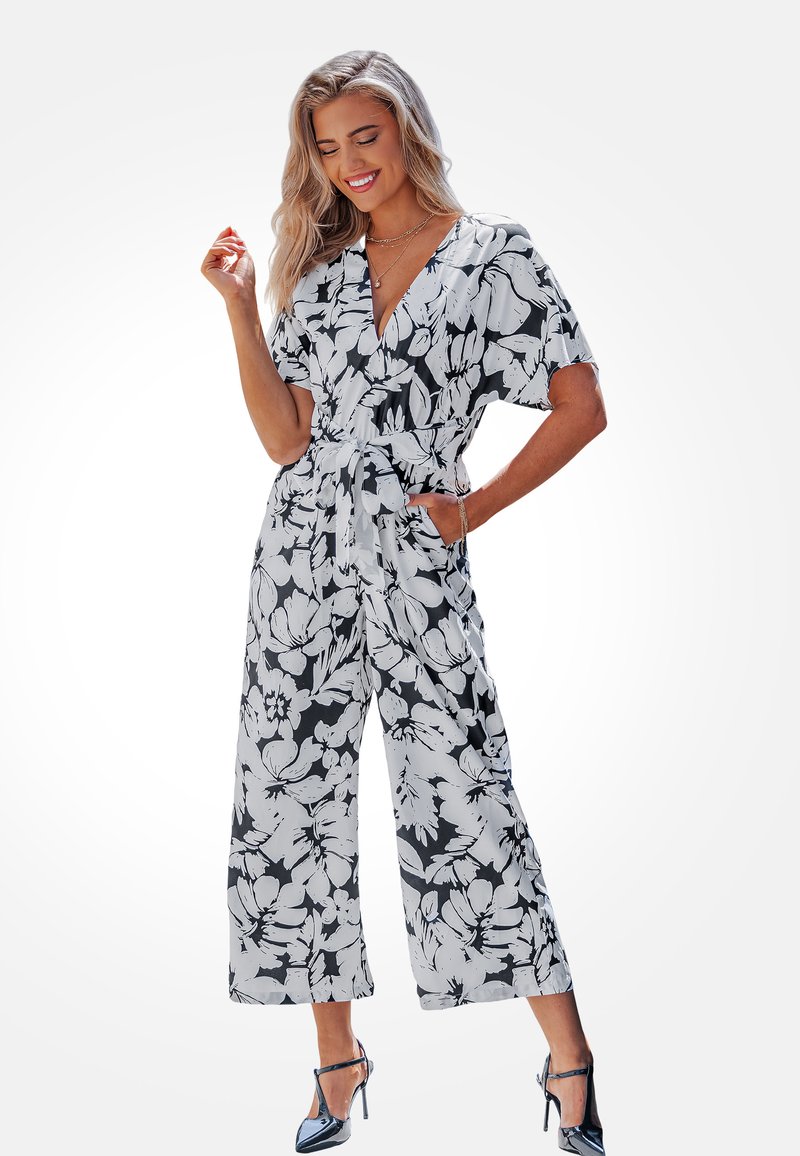 Bloemen jumpsuit in zwart en wit, met korte mouwen, een V-hals, een cinched taille met een strik, en wijde pijpen. Soepele stoftextuur.