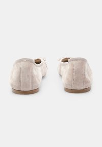 Svijetlosmeđi nubuk cipele s glatkom teksturom, okruglim vrhom i malom ravnom potplatom. Elastični detalj oko gležnja i jednostavni vezice.
