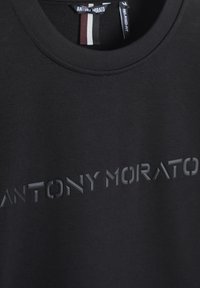 T-shirt nera in cotone con testo in rilievo "ANTONY MORATO" sul petto. Collo rotondo classico, vestibilità rilassata, texture liscia.