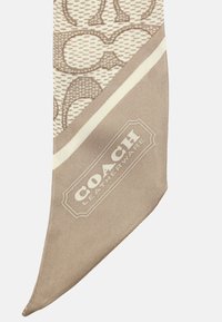 Cravatta in seta beige con un motivo a forme intrecciate, una striscia di colore crema in contrasto e il logo "COACH Leatherware" alla base.