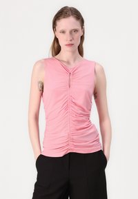 Rosa ärmlös topp med veckad design, nyckelhålsdetalj vid halsringningen och en slät textur, i kombination med svarta byxor.