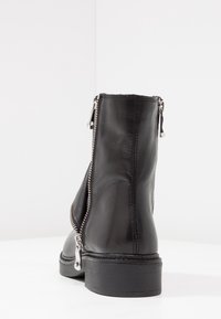 Czarne skórzane botki za kostkę z srebrnymi suwakami po bokach, teksturowane wykończenie i kontrastowe szwy. Solidna czarna gumowa podeszwa.