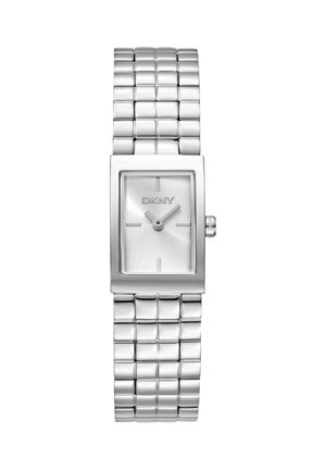 Montre rectangulaire argentée DKNY avec bracelet en métal, cadran minimaliste affichant 2h10, sans chiffres, petite couronne sur le côté droit.