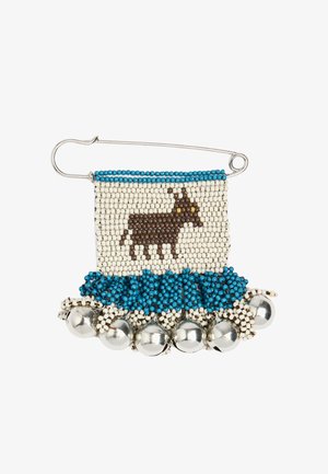 Szpilka bezpieczeństwa z obszyciem z koralików przedstawiająca brązowe zwierzę z żółtymi oczami, niebieską lamówką i srebrnymi dzwoneczkami przymocowanymi u dołu.