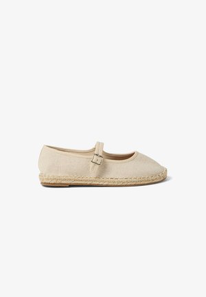 Alpargata plana de lona beige con puntera redonda, correa ajustable con hebilla y suela de yute trenzado sobre un fondo blanco.