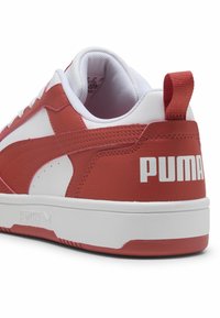 Piros és fehér sportcipő sima bőr felsőrésszel, lekerekített formával, kontrasztos fehér részletekkel és feltűnő "PUMA" logóval a sarkán.