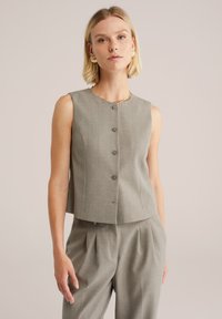 Sivý bezrukávový crop top s piatimi prednými gombíkmi, strih prispôsobený postave a jemnou textúrou. Vhodne doplnený o zladené sivé nohavice.