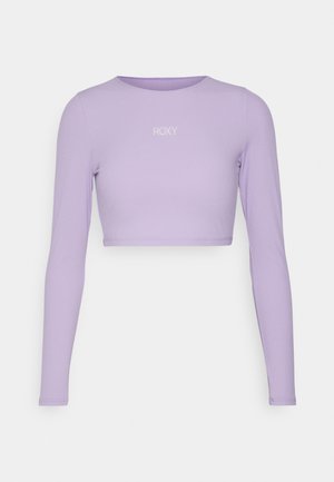 Fialový krátky crop top s dlhými rukávmi vyrobený z elastického materiálu, s jednoduchým okrúhlym výstrihom a bielym logom "ROXY" na hrudi.