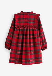 Vestido de cuadros rojos con mangas largas, cuello y puños con volantes, cintura fruncida y cierre de botones en la parte posterior. El patrón presenta líneas verdes y amarillas.
