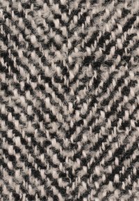 Schwarz-weiß gestrickter Stoff mit einem Zickzackmuster, der eine weiche, strukturierte Oberfläche und sichtbare Fäden aufweist.