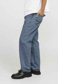 Rett ben leirdin jeans med en falmet vask, synlig søm og en sidelomme. Kombinert med svarte snøresko.