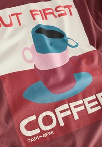 Bordo audinys su grafika, vaizduojančia rožinių ir mėlynų kavos puodelių krūvą, kartu su tekstu „PIRMIAUSIA KAVA 7:00–16:00“.