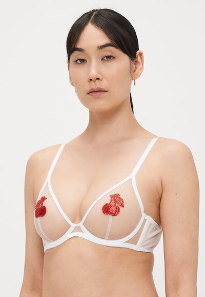 Beli mrežasti nedrček s trikotnimi košaricami, okrašen z rdečimi vezenimi češnjevimi aplikacijami. Tanki naramnice in minimalistična geometrijska zasnova.