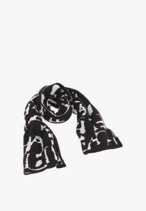 Schwarz-weiß gemusterter Schal aus weichem Material mit abstrakten Designs. Er hat eine lange, rechteckige Form und eine flauschige Textur.