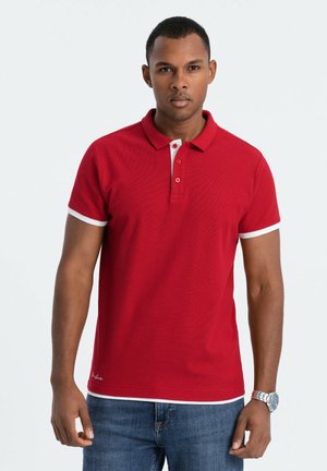 Rød polo shirt med hvide detaljer ved kraven og ærmeenderne, fremstillet af et tekstureret stof, to knapper og en diskret logo detalje ved kanten.