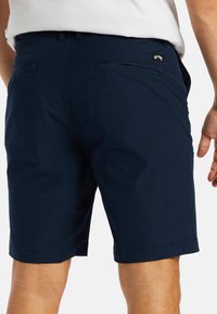 Navy blue shorts made of lightweight fabric, featuring a flat front, two back pockets, and stitching at the hem.