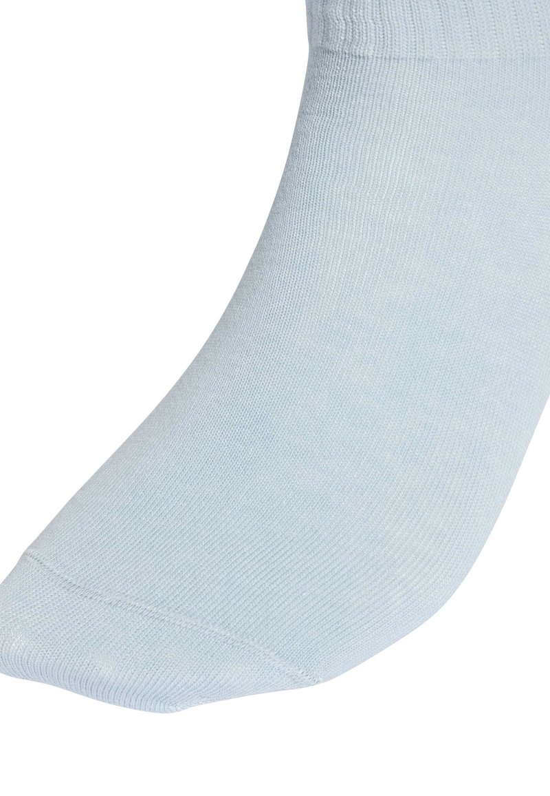 Gros plan sur un tissu tricoté bleu clair couvrant un pied, montrant la texture et la zone des orteils sans couture.