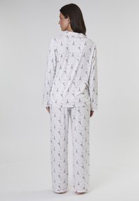 Set di pigiama bianco con un motivo a ripetizione della Torre Eiffel e cuori in rosa chiaro e grigio. Maniche lunghe e pantaloni larghi. Tessuto morbido.