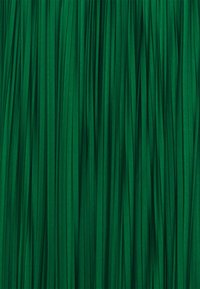 Tessuto plissettato verde con una superficie liscia, caratterizzato da sottili pieghe verticali. Il colore ricco è uniforme in tutto il tessuto, creando un aspetto omogeneo.