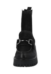 Botas negras hasta el tobillo con suela gruesa, parte superior de cuero suave, detalle de correa con herrajes de plata y un tirador en la parte posterior para un calzado fácil.