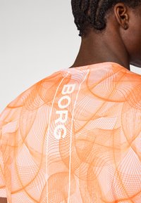 Orange kortærmet t-shirt med meshmønster, der har hvid tekst "BORC" lodret langs ryggen, rund halsudskæring og glat tekstur.
