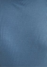 Niebieska dzianina ribbed z pionowymi paskami, charakteryzująca się gładką fakturą i dopasowanym krojem.