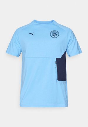 Lys blå kortærmet t-shirt med en marineblå lomme, med rund halsudskæring, Puma-logo og Manchester City-emblem på brystet.