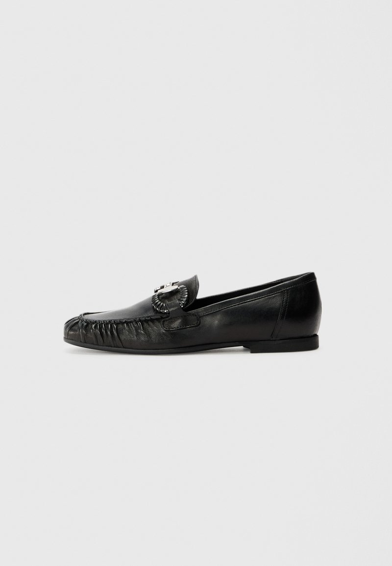 Black leather loafers with soft, textured finish, featuring a decorative buckle and gathered fringe detail on the front. Low heel.
