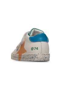 Sneaker in pelle bianca con tallone blu, design a stella arancione, impronta verde '@74' e texture della suola maculata. Chiusura con strap in Velcro.