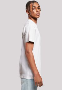 Weißes Baumwoll-T-Shirt mit kurzen Ärmeln, rundem Ausschnitt und lässiger Passform, vor einem neutralen Hintergrund präsentiert.