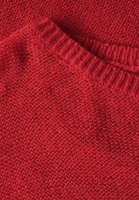 Roter Strickpullover mit einem strukturierten, offenen Maschenmuster. Der gerippte Ausschnitt verleiht dem weichen, warmen Stoff Struktur.