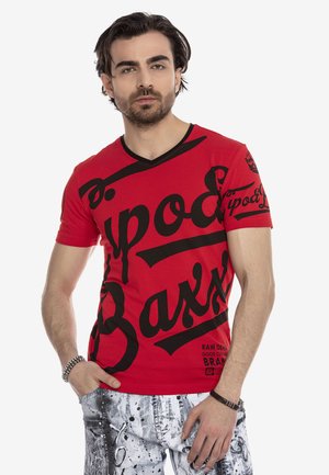 Rotes T-Shirt mit kurzen Ärmeln, kombiniert mit schwarzem grafischem Text und Mustern. Es hat ein V-Ausschnitt-Design und eine schlanke Passform. Das Material wirkt glatt.
