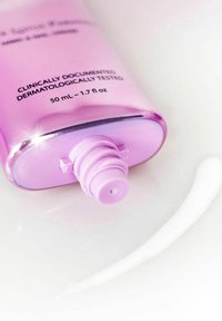 Lila Kunststoffflasche mit Drehverschluss, 50 ml Fassungsvermögen. Enthält eine glatte, weiße Creme, die auf einer glänzenden Oberfläche liegt.