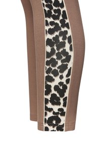 Braune Leggings mit einem Seitenpanel im Leopardenmuster, das eine weiche Textur und eine enganliegende Form aufweist. Das Panel kontrastiert mit schwarzen und cremefarbenen Nuancen.