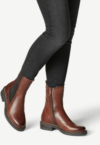 Braune Leder Stiefeletten mit seitlichen elastischen Einsätzen, Reißverschluss hinten und strukturiertem Finish. Robuste schwarze Gummisohle für guten Halt.