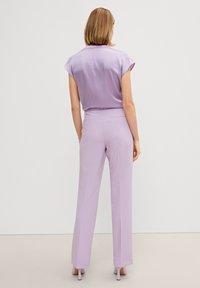Lila blus med kappaärmar och matchande högmidjade byxor, mjukt tyg, skräddarsydd passform, minimal detaljering, parat med ljusa klackar.