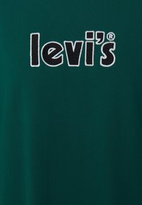 T-shirt in cotone verde scuro con un logo "levi's" nero ricamato in evidenza, arricchito da dettagli ricamati bianchi. Tessuto morbido e dalla texture piacevole.