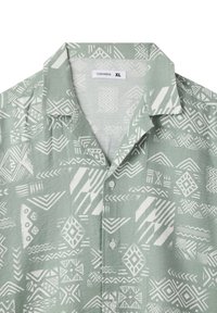 Camicia verde chiaro a maniche corte con motivi geometrici bianchi e colletto. Include chiusure a bottoni sul davanti.