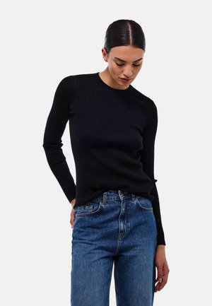 Pull noir à manches longues côtelé avec un col rond, associé à un jean en denim bleu à taille haute. Texture lisse et design ajusté.