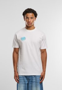 Hvit bomullst-skjorte med korte ermer, med en lyseblå sirkulær logo på venstre bryst og en vanlig passform.