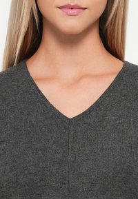 Maglione grigio a scollo a V realizzato in morbido materiale lavorato a maglia, con una superficie leggermente texturizzata e un design pulito e minimalista.