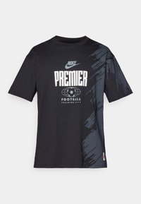 Sort kortærmet t-shirt med et gråt abstrakt mønster på den ene side. Har "Nike" logo og teksten "Premier Football Training Gear" i hvid.