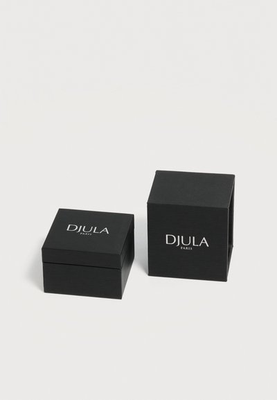 Deux boîtes à bijoux noires DJULA Paris, une fermée et une légèrement ouverte, placées sur une surface blanche.