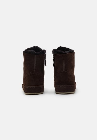 Bottines en suede marron avec une douce doublure en fourrure sombre. Comprend une semelle cousue et une fermeture éclair sur le côté pour un accès facile.