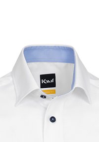 Camicia bianca con una vestibilità moderna, caratterizzata da un colletto interno blu chiaro e un bottone blu. L'etichetta mostra la scritta "Kauf" con accenti gialli.