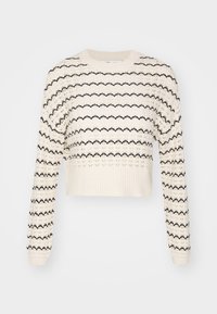 Pull cropped en crochet crème avec un motif zigzag noir, manches longues et ourlet côtelé. Fabriqué en tissu tricoté texturé.