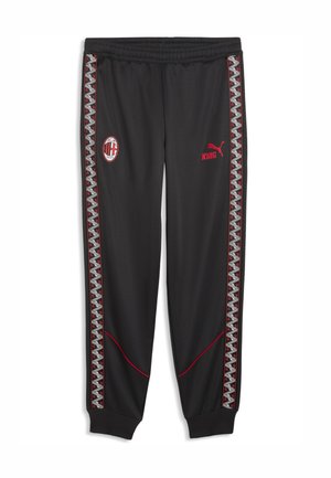 Czarne spodnie dresowe z zygzakowatymi paskami po bokach, herb AC Milan po lewej, czerwone logo Pumy i napis "KING" po prawej, elastyczny pas.